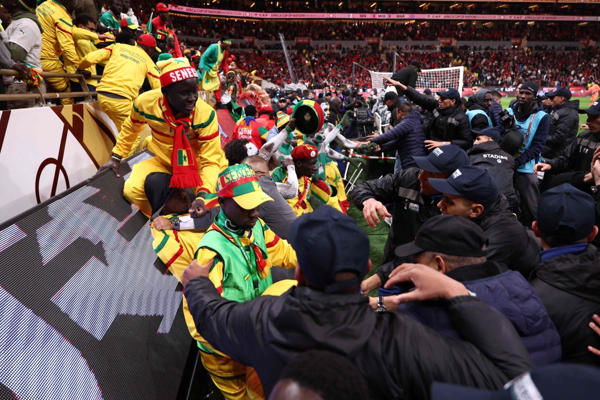 Fans scuffle with security personnel as they storm the field after a penalty decision against Senegal during the Africa Cup of Nations (CAN) final football match between Senegal and Morocco at the Prince Moulay Abdellah Stadium in Rabat on January 18, 2026. (Photo by Franck FIFE / AFP)