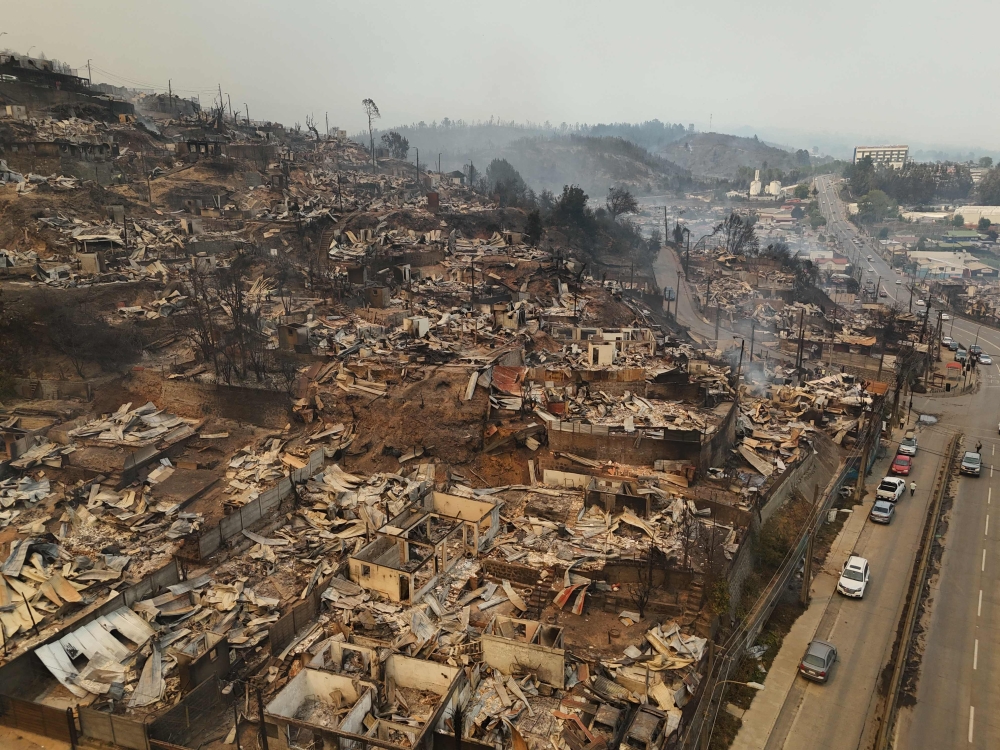 Aerial view of the charred remains of destroyed homes after a wildfire in Concepcion, Chile, on January 18, 2026. Chilean President Gabriel Boric declared a state of emergency on January 18 for two southern regions where raging wildfires have forced about 20,000 people to evacuate their homes. (Photo by Raul Bravo / AFP)
