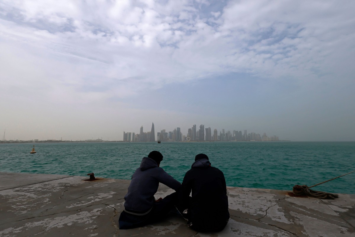 Visitors sit along the waterfront on a foggy day at the Corniche area facing the high-rise buildings in the West Bay district, in Doha on January 15, 2026. (Photo by Karim JAAFAR / AFP)
