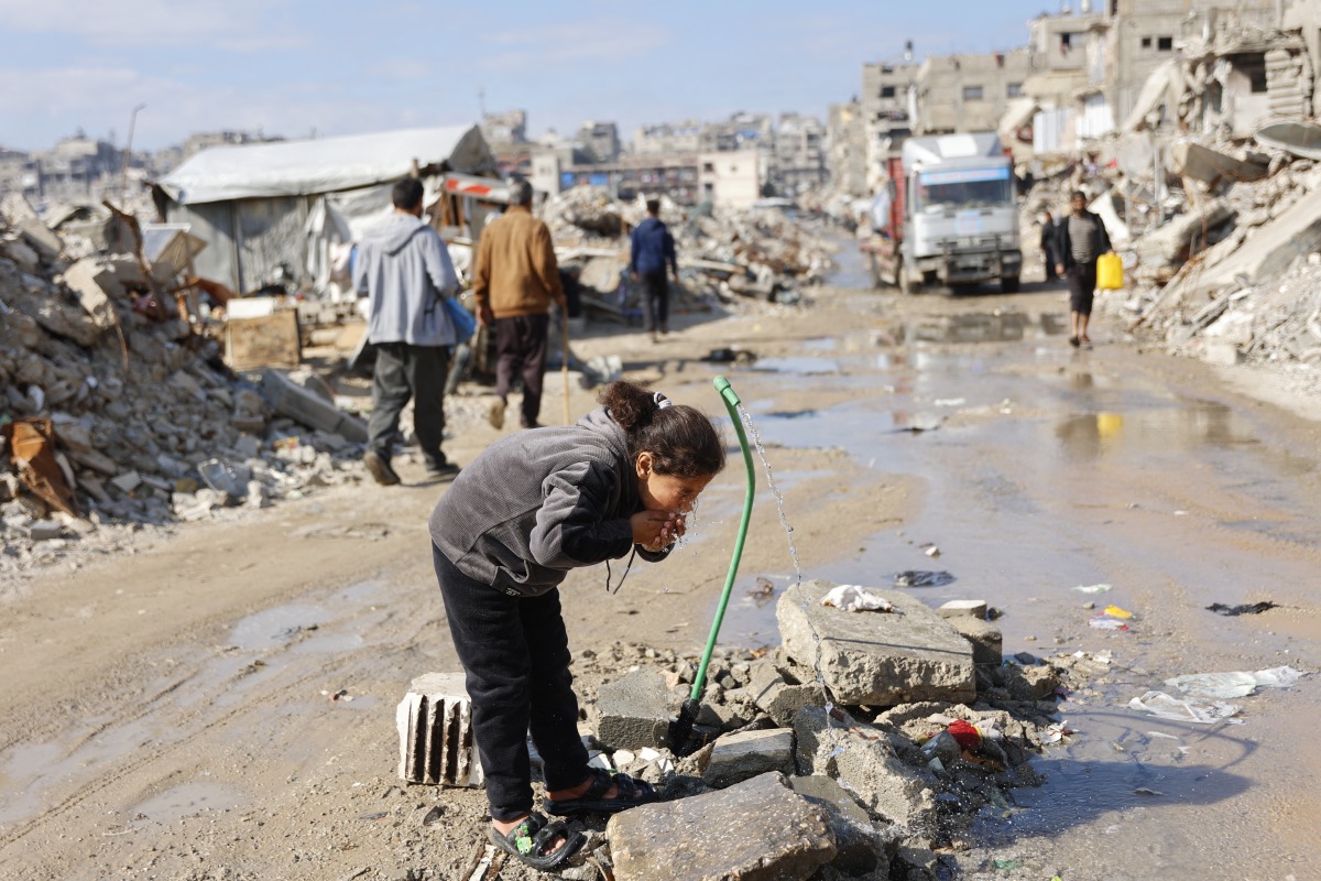 Displaced Palestinians live amongst the rubble and debris of homes and businesses destroyed by the Israeli military in over two years of military strikes on the Gaza Strip enclave, drinks water from a stand pipe, in Jabalia refugee camp, in the northern Gaza Strip on January 17, 2026. Photo by OMAR AL-QATTAA / AFP
