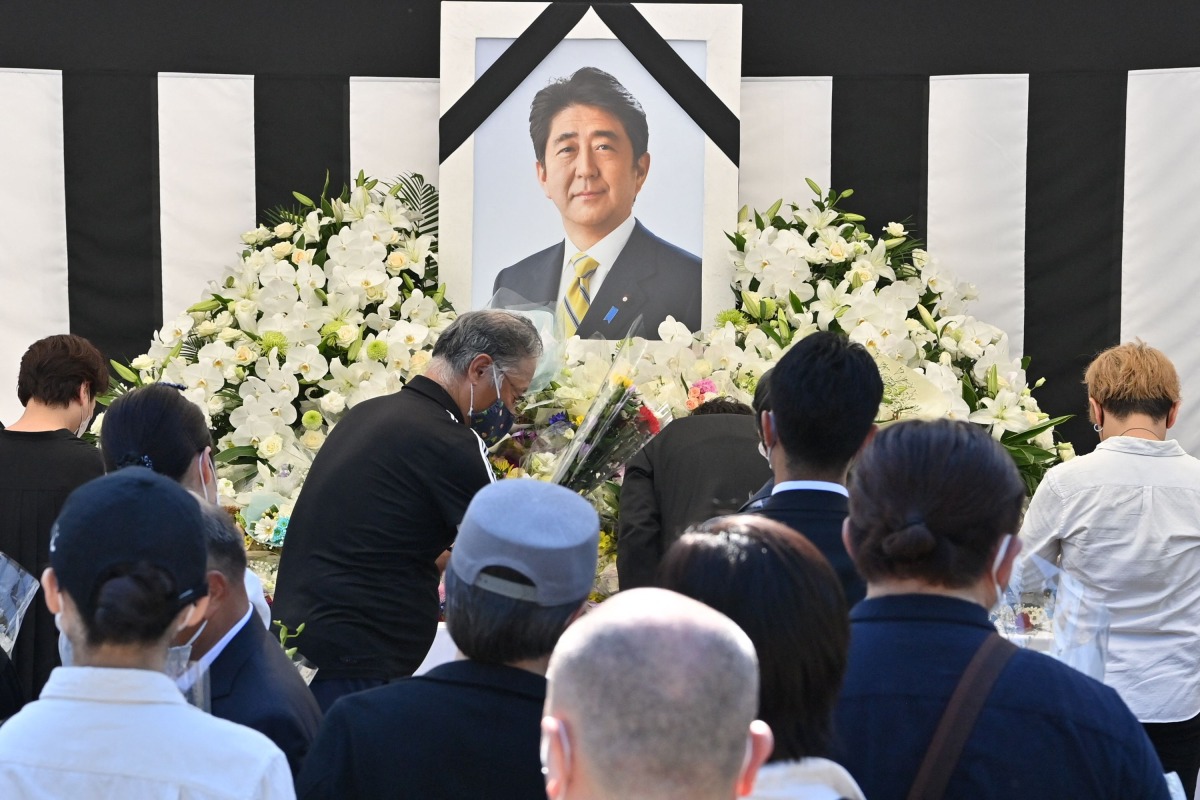 This photo taken on September 27, 2022 shows people offering their respects to former Japanese prime minister Shinzo Abe outside the Nippon Budokan in Tokyo, ahead of his state funeral later in the day. Photo by Yuichi YAMAZAKI / AFP