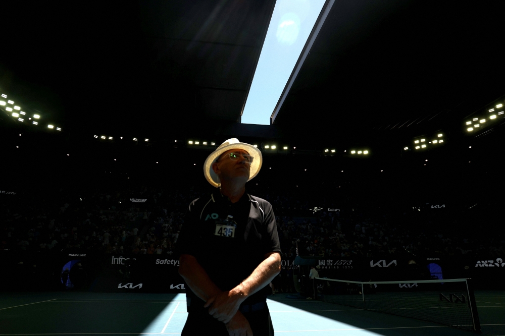A security officer looks on as the roof of Rod Laver Arena is closed due to extreme heat during the men's singles match between Italy's Jannik Sinner and USA's Eliot Spizzirri in Melbourne on January 24, 2026. (Photo by David Gray / AFP) 