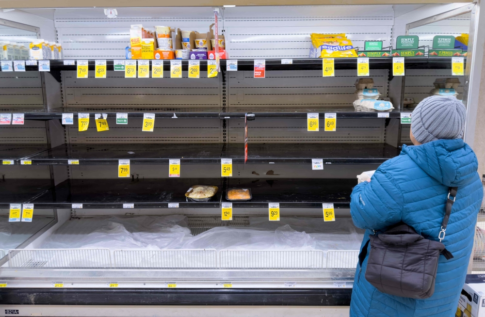 A person shops for eggs on mostly empty shelves as residents stock up ahead of a cold front expected in the area in Arlington, Virginia, on January 23, 2026. (Photo by Saul Loeb / AFP)