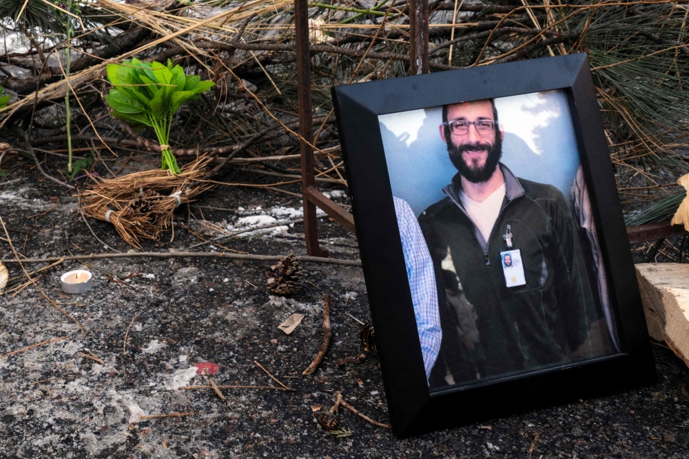 A photograph of 37-year-old Alex Pretti can be seen at a makeshift memorial in the area where he was shot dead by federal immigration agents earlier in the day in Minneapolis, Minnesota, on January 24, 2026. (Photo by Roberto Schmidt / AFP)