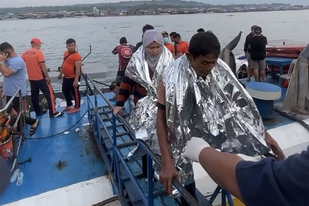 This screen grab from video footage taken and received on January 26, 2026 from Governor Mujiv Hataman shows rescuers assisting survivors of the sunken MV Trisha Kerstin 3 at a port in Isabela, Basilan province. (Photo by Handout / Governor Mujiv Hataman / AFP)