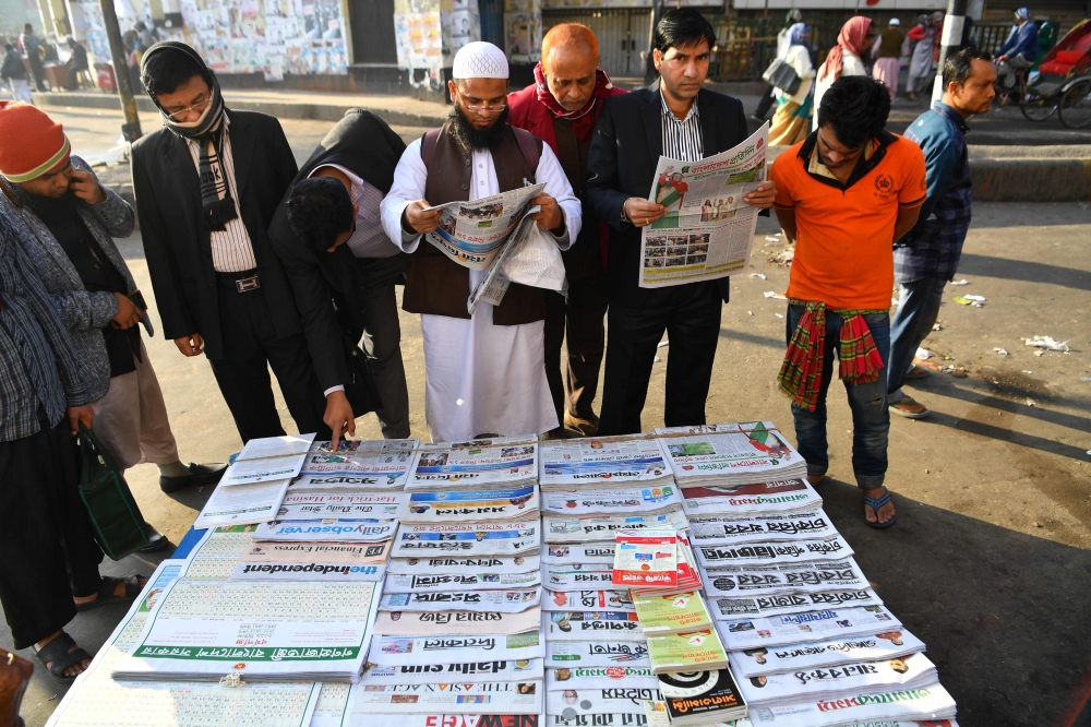 Representational file photo. Bangladeshi people read newspapers carrying headlines of the general election results in Dhaka on December 31, 2018. AFP / Indranil MUKHERJEE