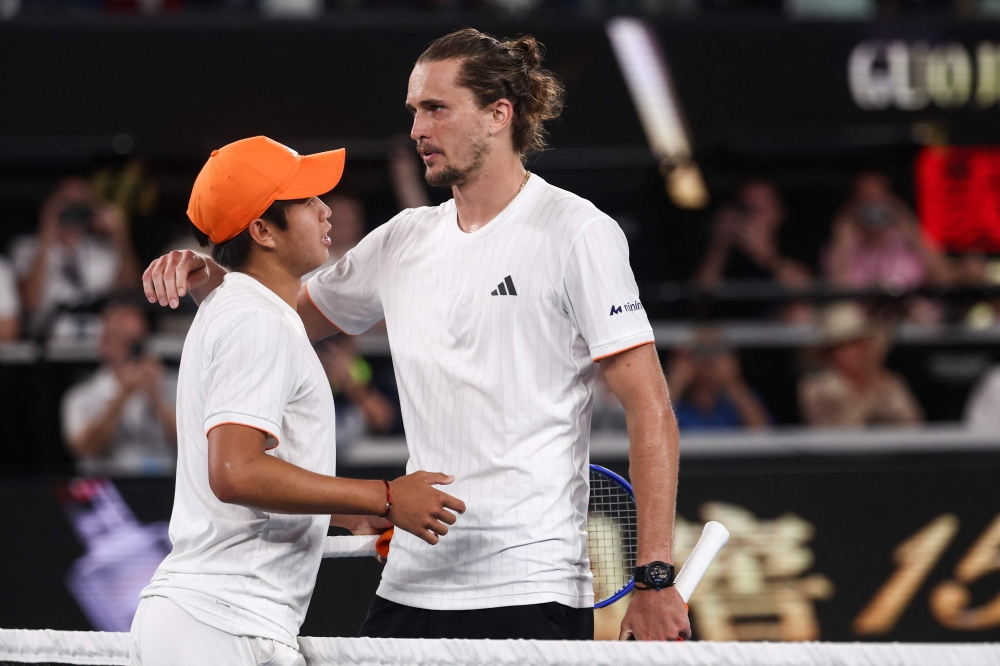 Germany's Alexander Zverev (R) and USA's Learner Tien embrace at the net after their men's singles quarter-final match on day ten of the Australian Open tennis tournament in Melbourne on January 27, 2026. (Photo by Izhar Khan / AFP) 