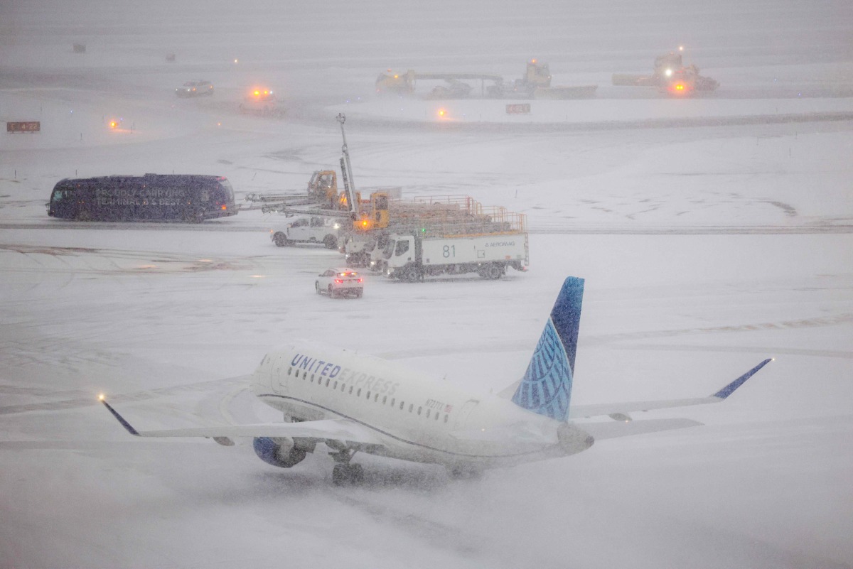 An Embraer 175 of United airlines taxies to take off as the snow falls on the tarmac of LaGuardia airport in New York on January 25, 2026. Photo by CHARLY TRIBALLEAU / AFP