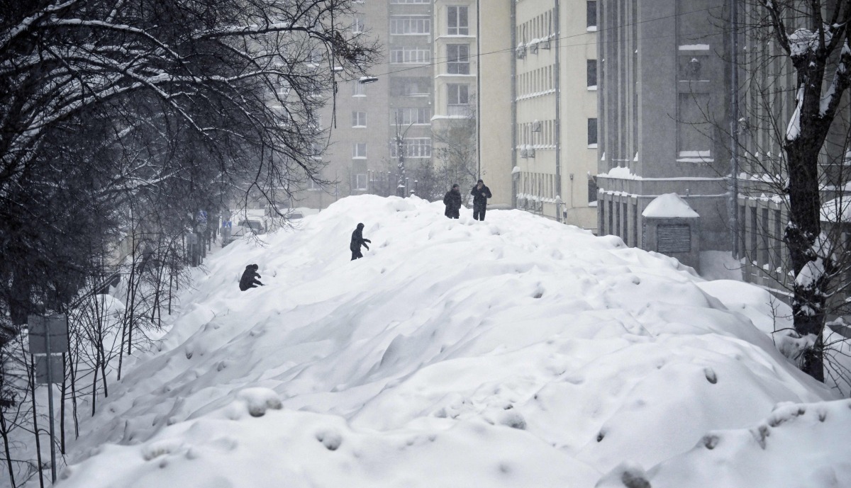 People cross a street used for temporary snow storage in central Moscow on January 29, 2026. (Photo by Alexander NEMENOV / AFP)
