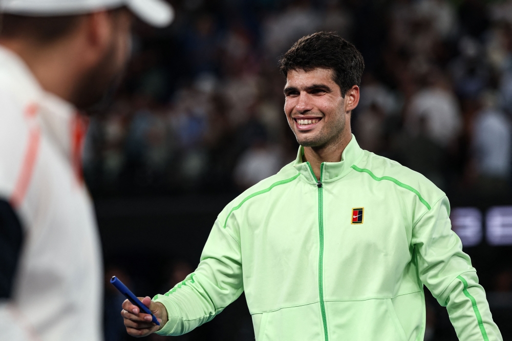 Spain's Carlos Alcaraz signs a television camera after beating Germany's Alexander Zverev in Melbourne on January 30, 2026. (Photo by Izhar Khan / AFP) 