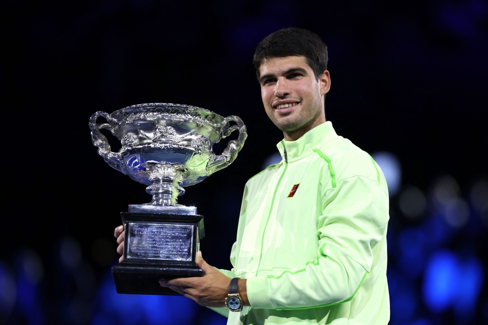 Spain's Carlos Alcaraz poses with the Norman Brookes Challenge Cup after defeating Serbia's Novak Djokovic in Melbourne on February 1, 2026. (Photo by Martin Keep / AFP)