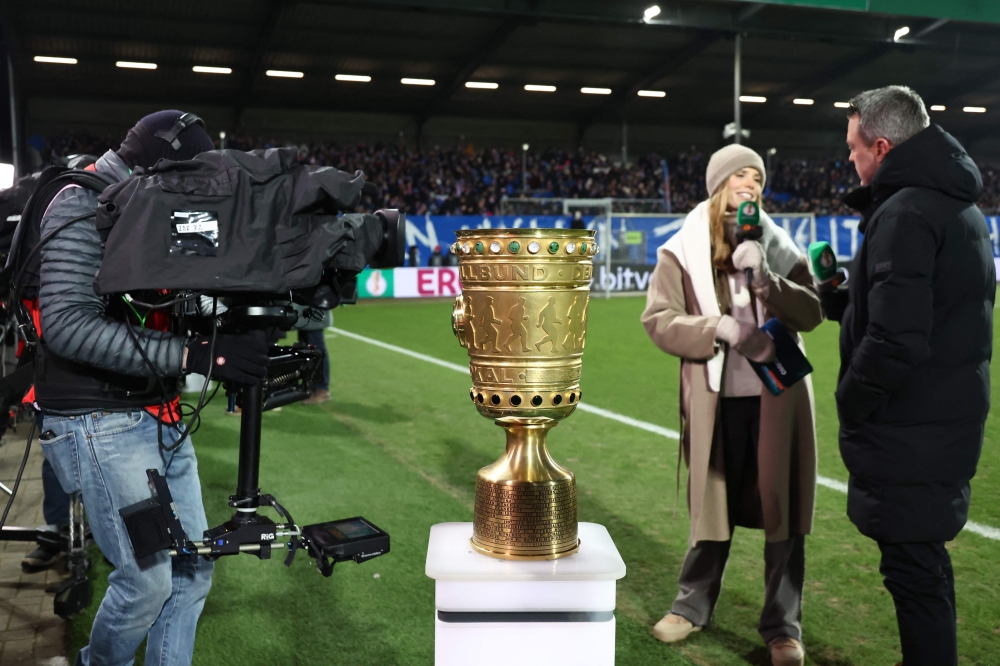 Media representatives are seen by the German Cup trophy displayed prior to the start of the German Cup (DFB-Pokal) quartefinal football match between Holstein Kiel and VfB Stuttgart in Kiel, northern Germany on February 4, 2026. (Photo by Ibrahim OT / AFP) 