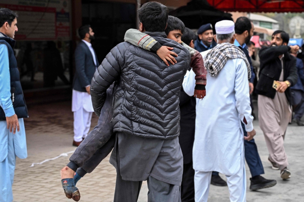 A man carries an injured boy to a hospital following an explosion at a mosque in Islamabad on February 6, 2026. (Photo by Aamir Qureshi / AFP)