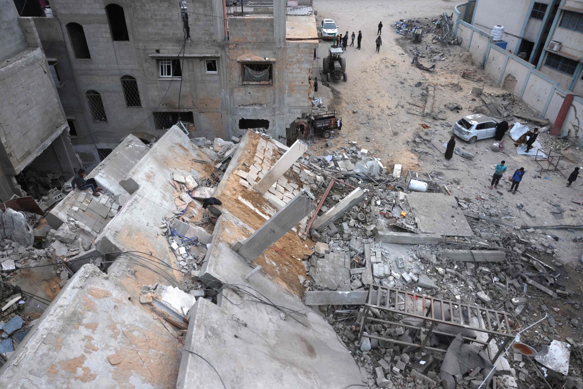 Displaced Palestinians inspect the damage after Israeli aircraft targeted a five floor house last night, in Khan Yunis southern Gaza Strip on February 6, 2026. (Photo by Bashar Taleb / AFP)