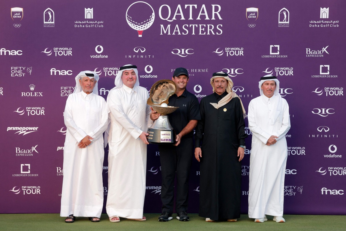 US' Patrick Reed celebrates on the podium with the trophy after winning the Qatar Masters 2026 golf tournament at Doha Golf Club in Doha on February 8, 2026. (Photo by Karim JAAFAR / AFP)
