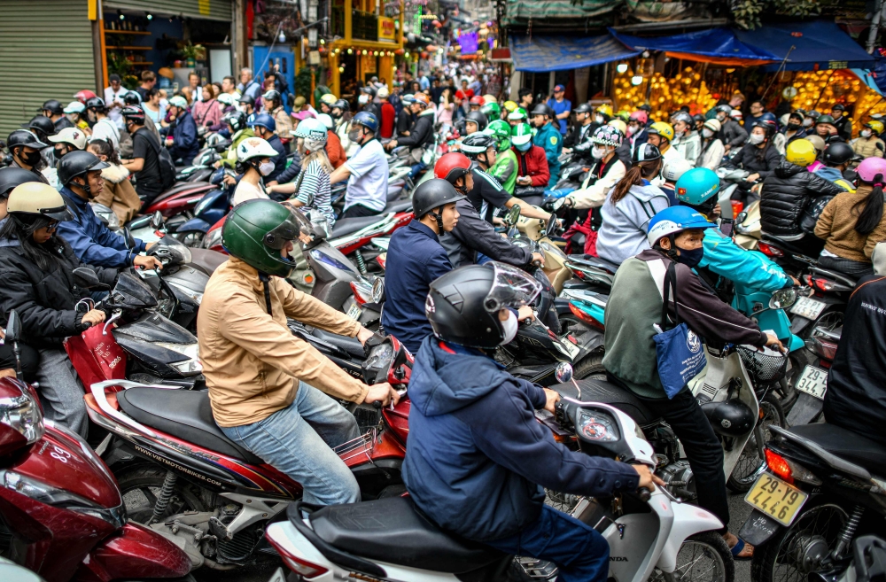 Motorists cross railway tracks on the motorbikes after a train passed on the popular train street in Hanoi on February 13, 2026. (Photo by Amaury Paul / AFP)