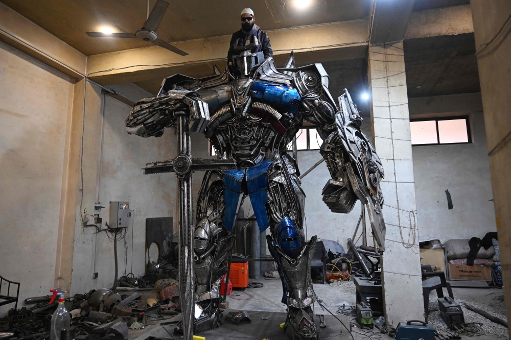 This photograph shows a worker weilding scrap metal into Optimus Prime, a film character from Transformers, at a studio on the outskirts of Islamabad. Sparks fly and metal groans in a cavernous workshop on the outskirts of Islamabad, where Pakistani artist Ehtisham Jadoon fuses discarded car parts into colossal pieces inspired by 