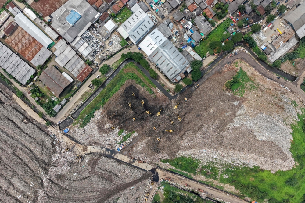 This aerial picture shows a rescue team using heavy machinery to search for people following a landslide at Bantargebang landfill in Bekasi, West Java, on March 9, 2026 (Photo by Bay Ismoyo / AFP)