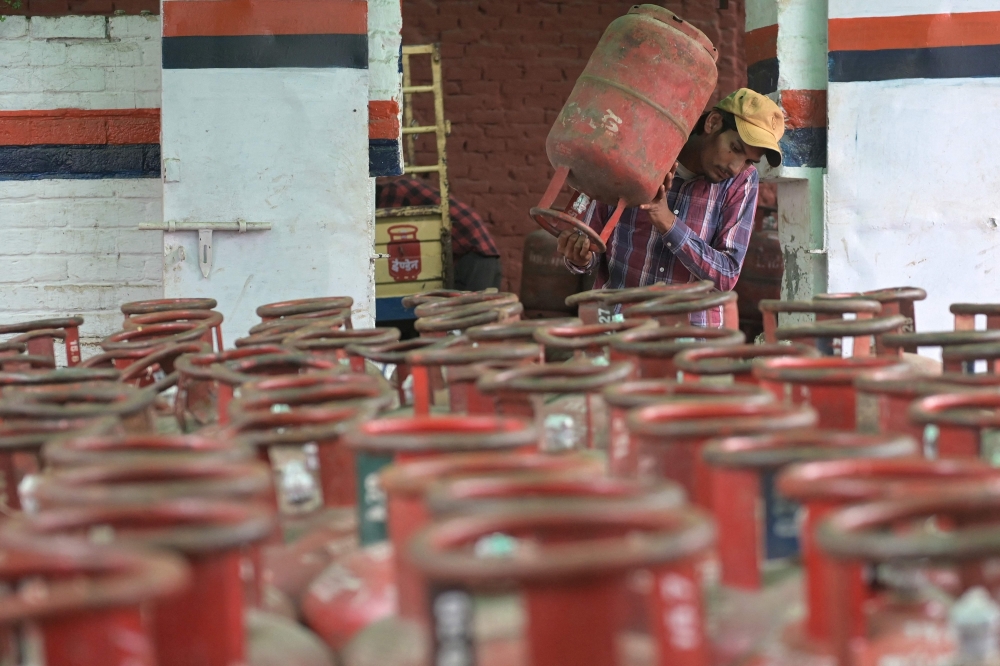 A  delivery staff carries liquefied petroleum gas (LPG) cylinders at a distribution centre in Amritsar on March 10, 2026. (Photo by Narinder Nanu / AFP)