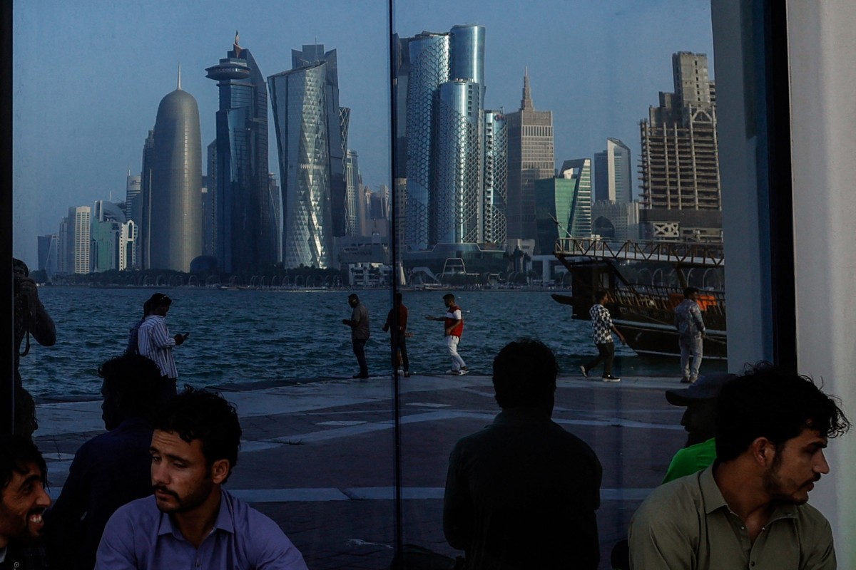 People sit with the reflection of the Doha skyline along the Doha Corniche, on the second day of Eid al-Fitr celebrations marking the end of the Muslim holy month of Ramadan, in Doha on March 21, 2026. Photo by AFP
