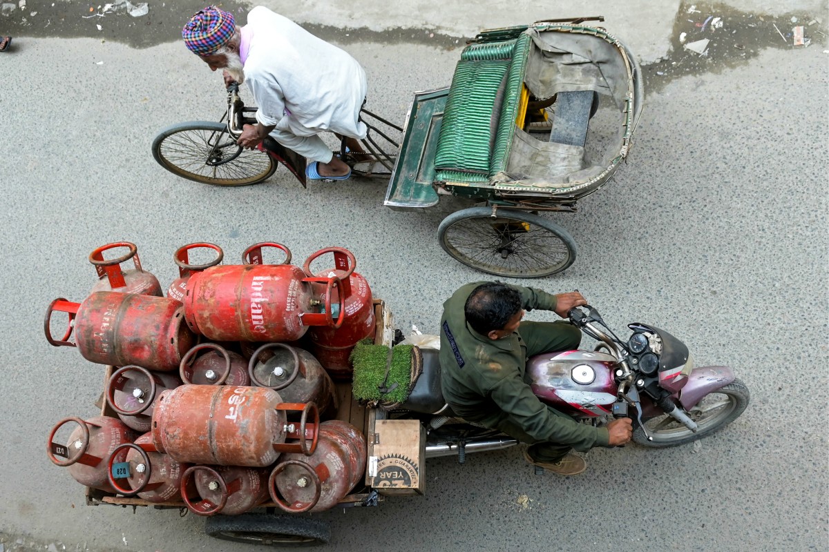 A delivery man transports liquid petroleum gas (LPG) cylinders in Amritsar on March 24, 2026. Photo by Narinder Nanu / AFP

