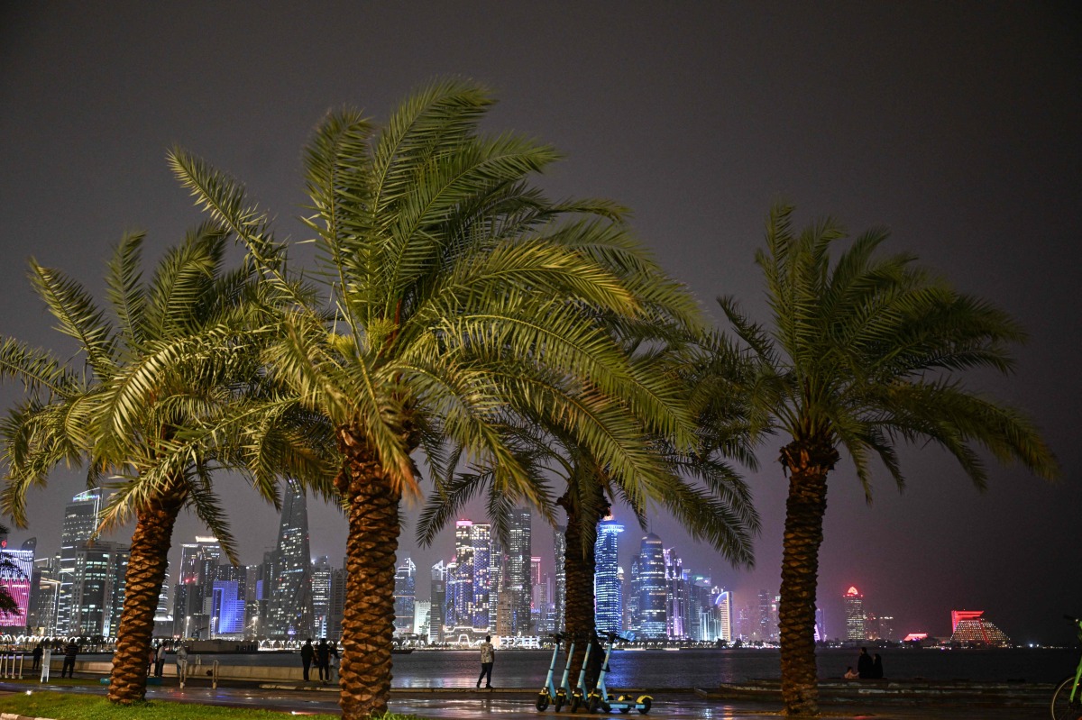 People walk along the Corniche area during a storm over Doha City in Qatar on March 26, 2026. (Photo by Mahmud HAMS / AFP)