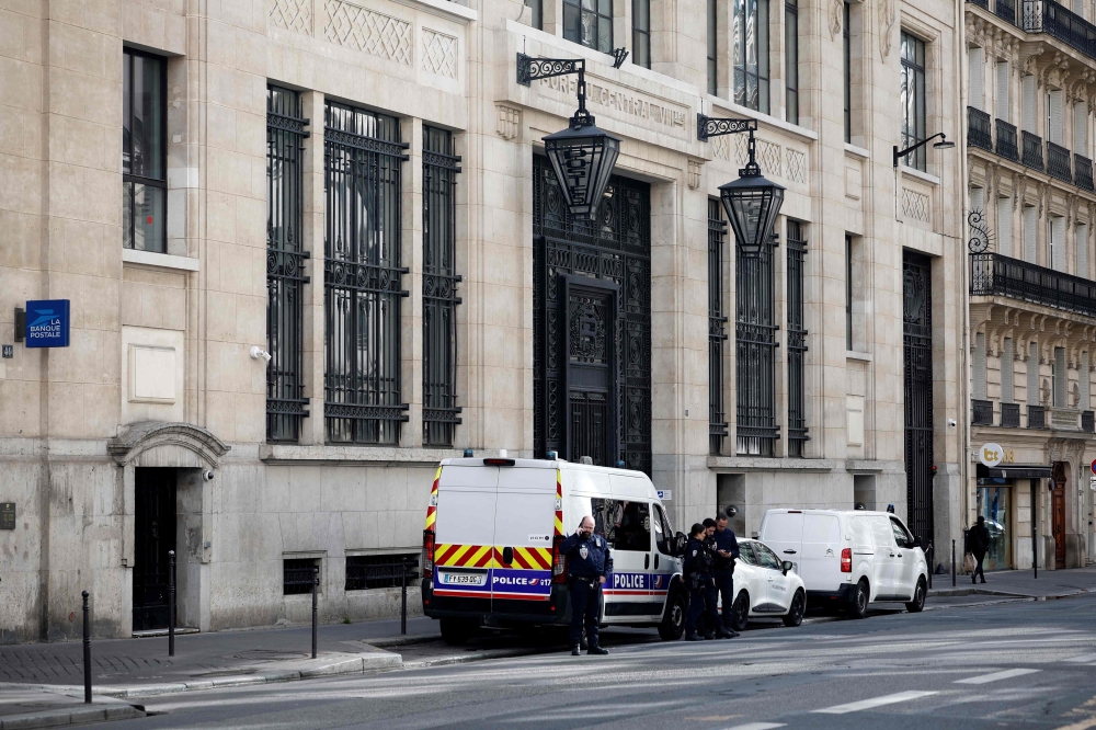 Police officials stand alongside police and private security vehicles outside The Bank of America building in the 8th arrondissement of Paris on March 28, 2026, following an apparent bomb attack attempt. (Photo by Sebastien Dupuy / AFP)
