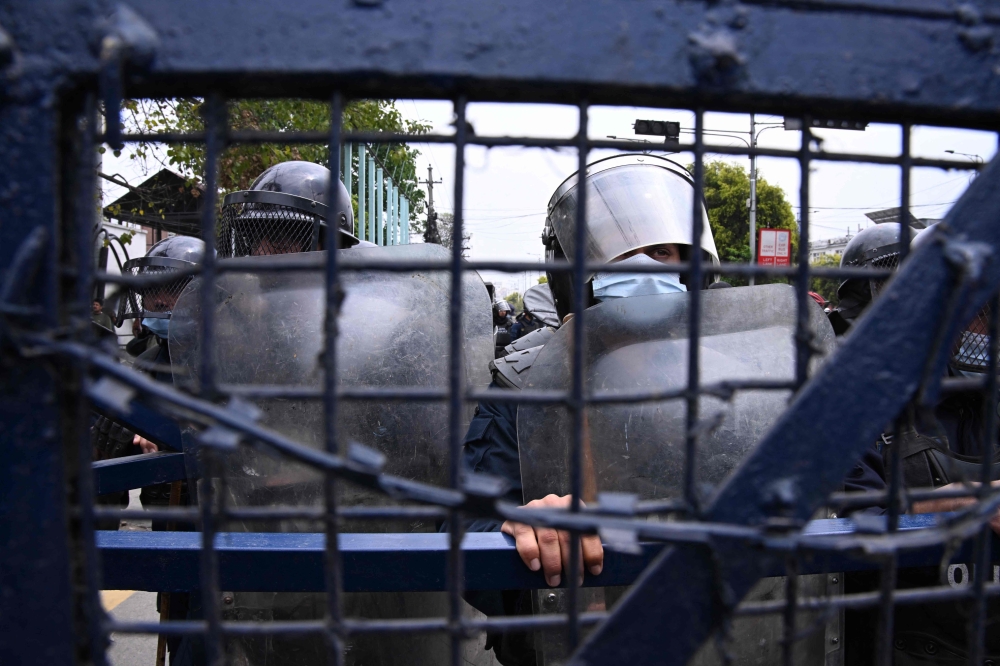 Police stand guard while Nepali former prime minister KP Sharma Oli's supporters protest against his arrest in Kathmandu on March 29, 2026. (Photo by Prakash Mathema / AFP)