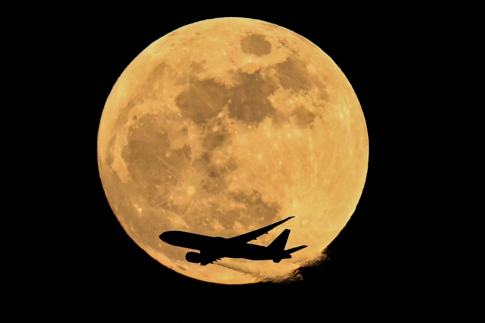 Air China cargo's airline Boeing 777-FFT aircraft flies past the April full moon in Frankfurt am Main, western Germany on April 1, 2026. (Photo by Kirill Kudryavtsev / AFP)