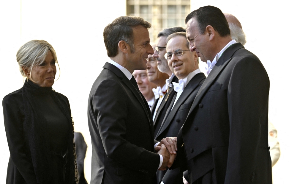 France's President Emmanuel Macron and his wife Brigitte Macron are welcomed by officials as they arrive in San Damaso courtyard before a meeting with Pope Leo XIV, in the Vatican on April 10, 2026. (Photo by Tiziana FABI / AFP)