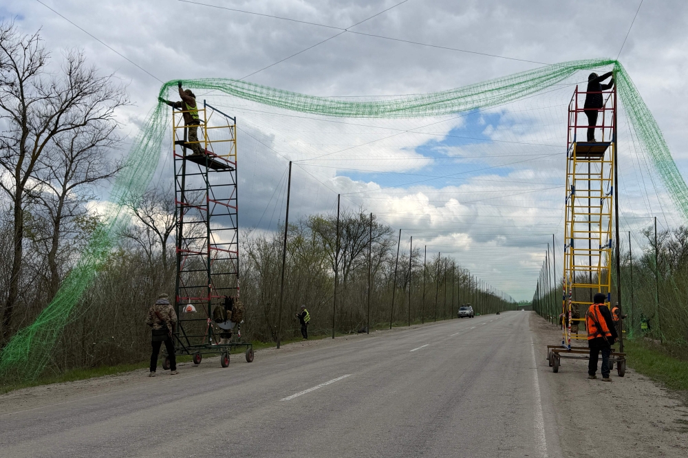 Ukrainian servicemen cover the road with a net to protect vehicles from drone attacks at an undisclosed location in the Zaporizhzhia region on April 10, 2026. (Photo by Darya Nazarova / AFP)