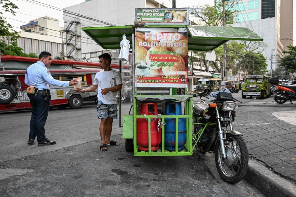 A man sells the popular breakfast roll 'pandesal' in Manila on April 7, 2026. (Photo by Jam Sta Rosa / AFP)