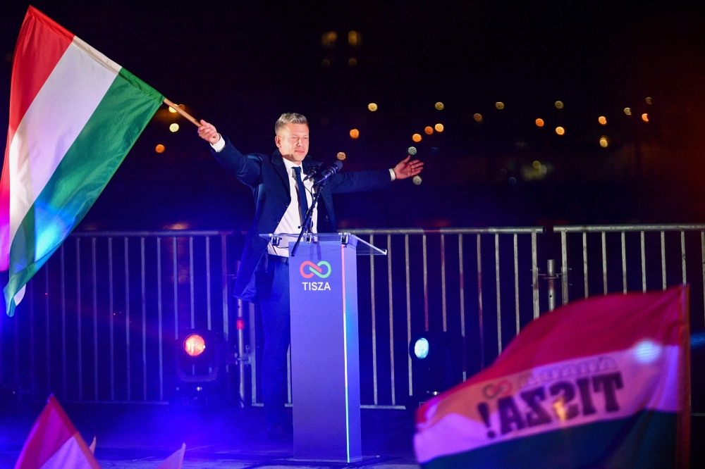 Peter Magyar, leader of the pro-European conservative TISZA party, waves the national flag during celebrations at the election night party in Budapest after the general election in Hungary, on April 12, 2026. (Photo by Ferenc Isza / AFP)