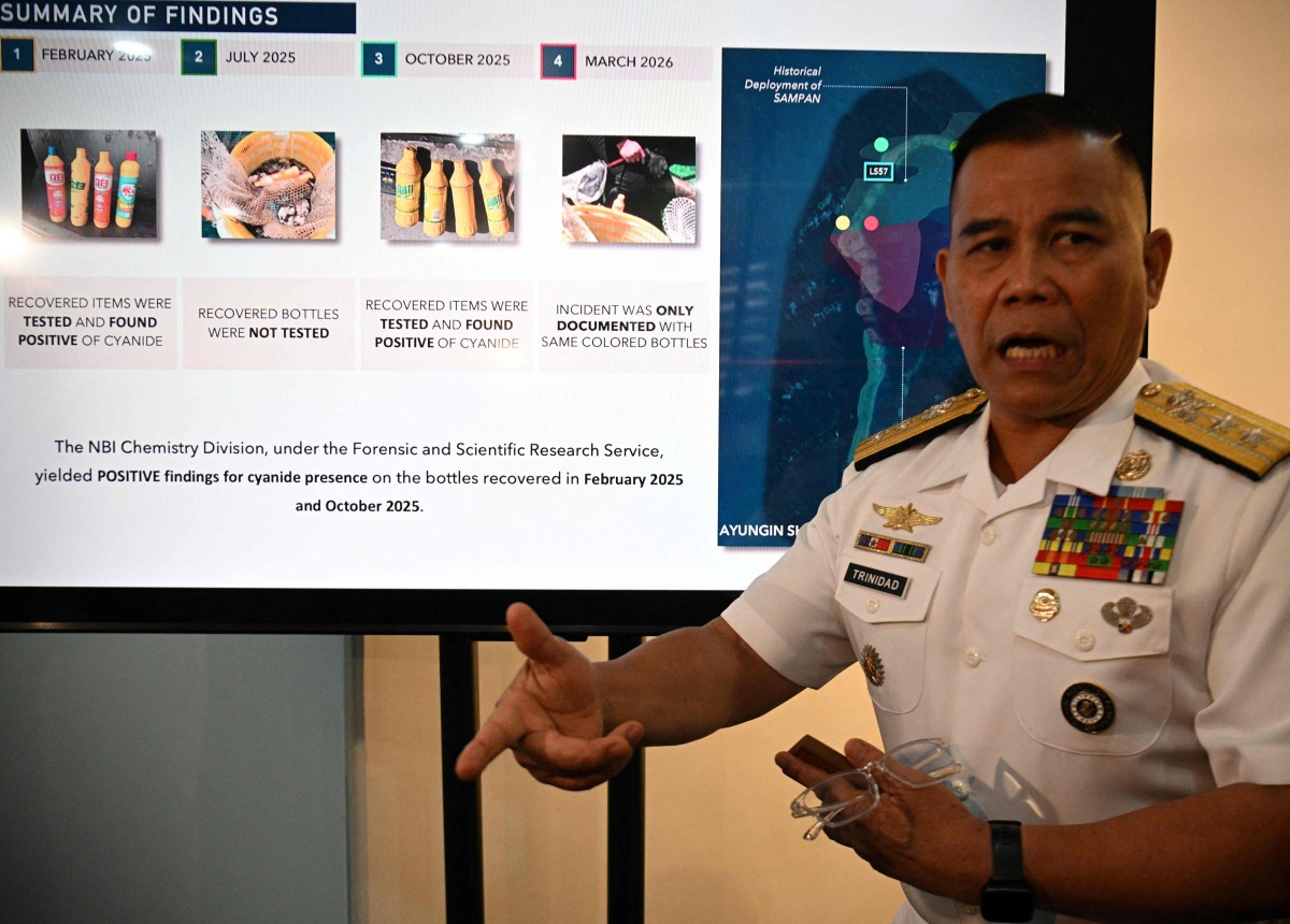 Philippine Navy spokesman Rear Admiral Roy Vincent Trinidad speaks next to a slide presentation of seized yellow bottles suspected to contain cyanide in waters of Second Thomas Shoal in the disputed South China Sea, during a press conference in Manila on April 13, 2026. Photo by Ted ALJIBE / AFP
