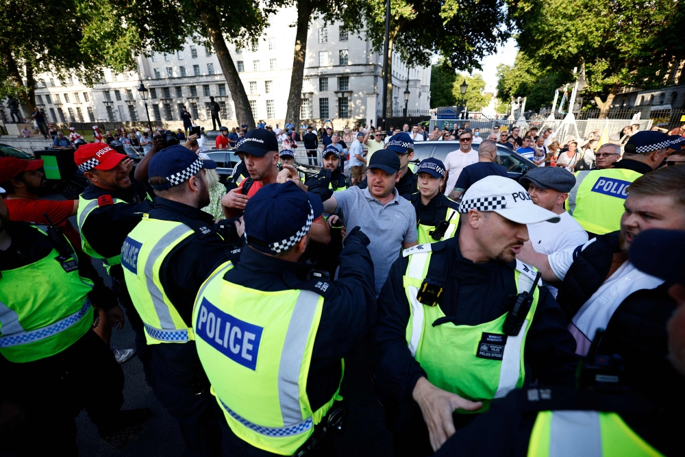 A protestor remonstrates with police officers during the 'Enough is Enough' demonstration on Whitehall, outside the entrance to 10 Downing Street in central London on July 31, 2024, held in reaction the Government's response to the fatal stabbings in Southport on July 29. (Photo by BENJAMIN CREMEL / AFP)