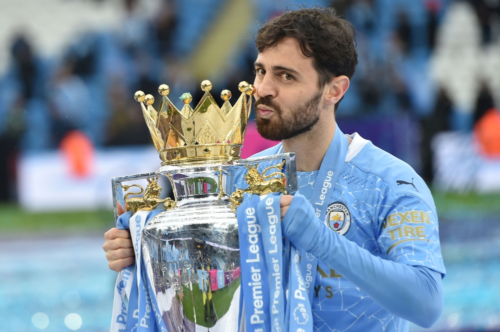(Files) Manchester City's Portuguese midfielder Bernardo Silva lifts the Premier League trophy in Manchester, north west England, on May 23, 2021. (Photo by Peter Powell / Pool / AFP)
