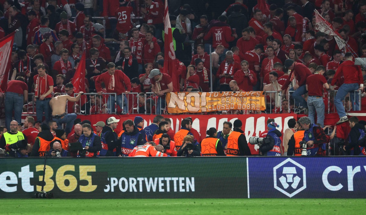 A photographer is treated after fans climbed over the fence after the UEFA Champions League quarter-final second leg football match between FC Bayern Munich and Real Madrid in Munich, southern Germany, on April 15, 2026. Photo by Karl-Josef HILDENBRAND / AFP