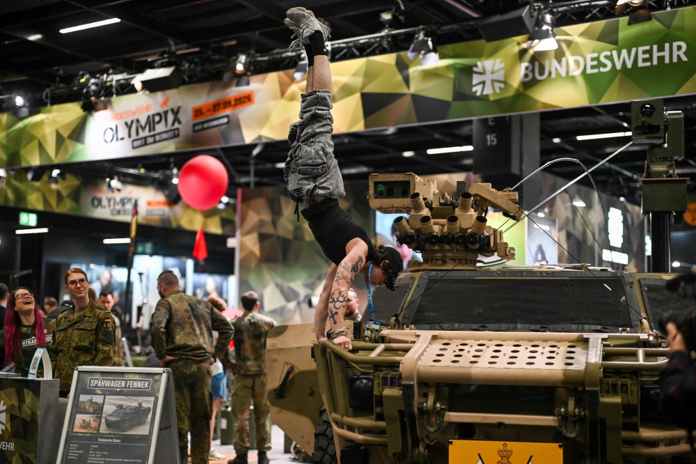 A visitor performs on a reconnaissance vehicle of the German Federal army Bundeswehr at their booth at the FIBO trade show for health, fitness and wellness in Cologne, western Germany on April 16, 2026. (Photo by Ina Fassbender / AFP)