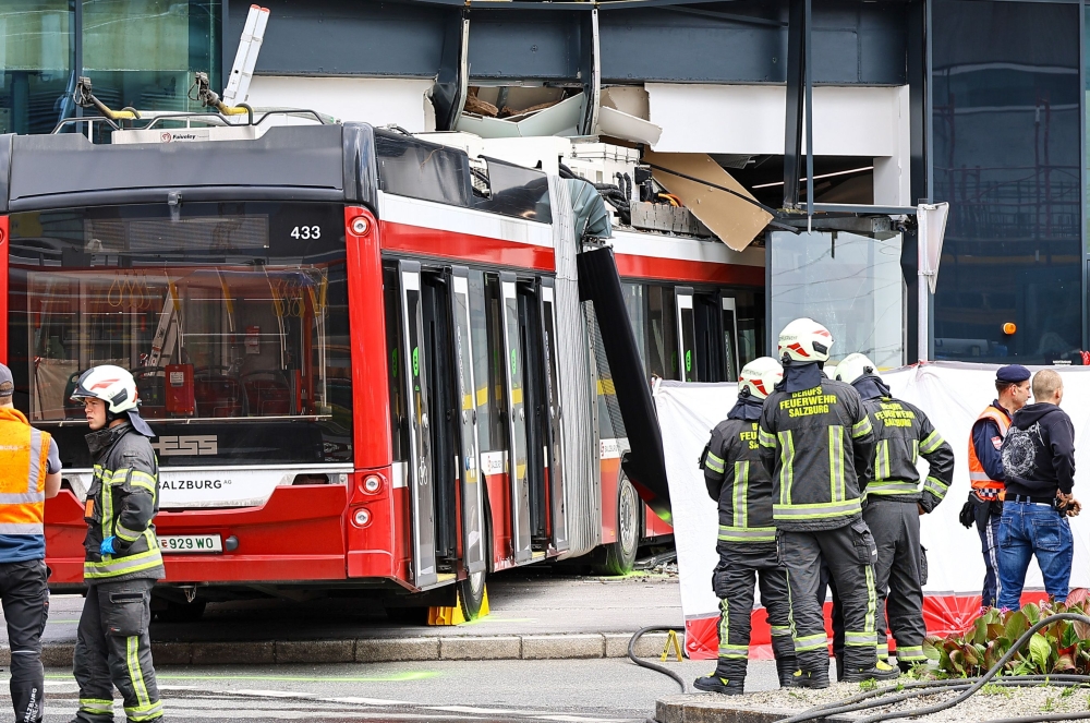 Firefighters and rescue personnel stand next to a trolleybus that crashed into a supermarket on April 20, 2026 in Salzburg, Austria. (Photo by various sources / AFP) 