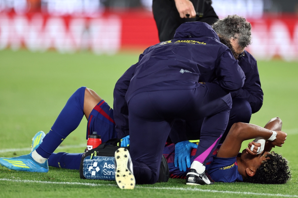Barcelona's Spanish forward #10 Lamine Yamal receives medical attention after sustaining an injury during the Spanish league football match between FC Barcelona and RC Celta de Vigo at Camp Nou stadium in Barcelona on April 22, 2026. (Photo by Josep Lago / AFP)