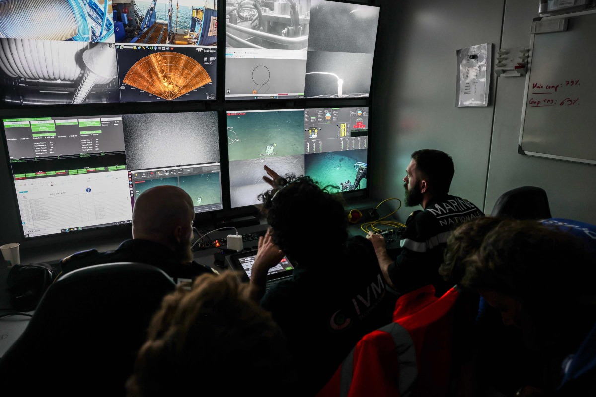 Pilots specializing in underwater robots from the French Navy, along with researchers, watch live feeds on screens showing the “ROV C 4000,” a remotely operated vehicle manufactured by the French company LD Travocean and designed for seabed exploration, during an archaeological mission on the wreck of the CAMARA 4 from the bridge of the (BSAA) Jason, off the coast of Ramatuel, in southeastern France, April 7, 2026. Photo by Thibaud MORITZ / AFP