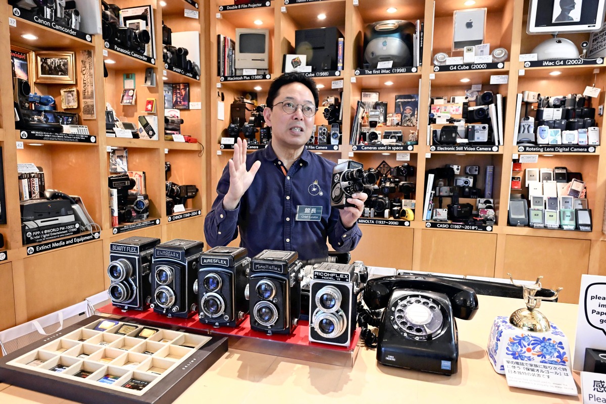 Takuya Kawai speaks while holding a camera. Photo credit: Japan News
