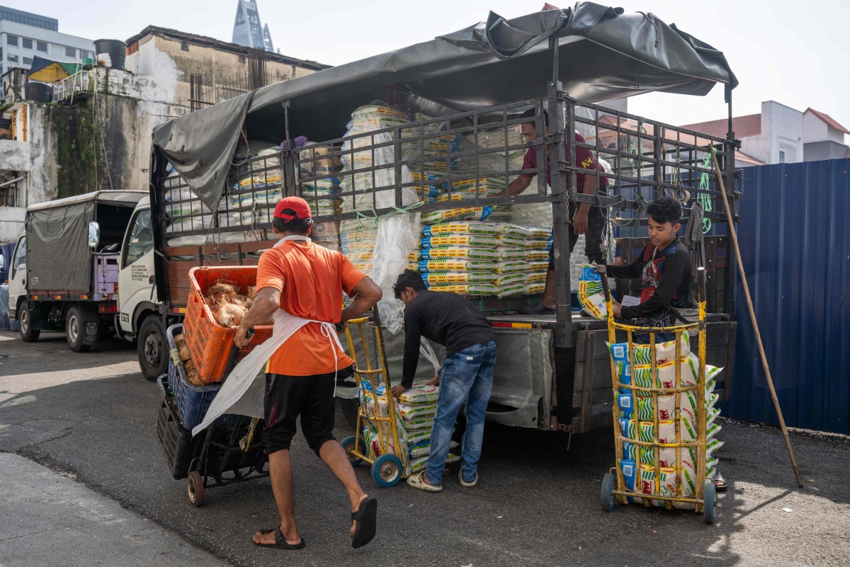 Workers unload sacks of rice outside a market in Kuala Lumpur on April 28, 2026. (Photo by Mohd Rasfan / AFP)