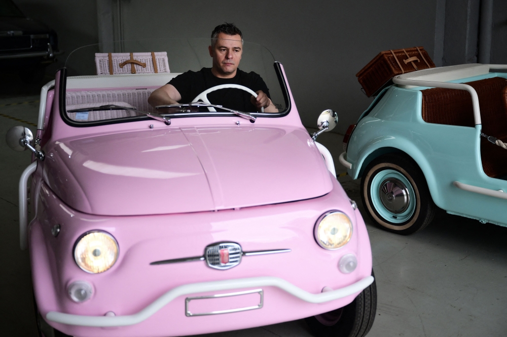 Owner of the Officine Gentile garage, Giovanni Gentile sits at the wheel of a model of a Fiat 500 Jolly Lido at his workshop in Turin on April 30, 2026. (Photo by Marco Bertorello / AFP)