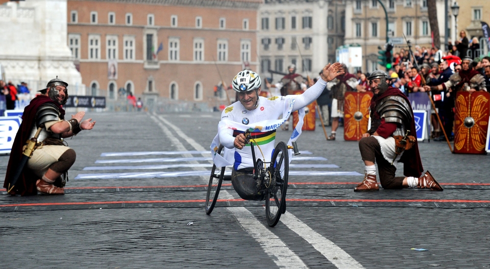 (Files) Former driver and paracyclist Alex Zanardi celebrates as he crosses the fininsh line of the 20th Marathon of Rome on March 23, 2014. (Photo by Tiziana Fabi / AFP)