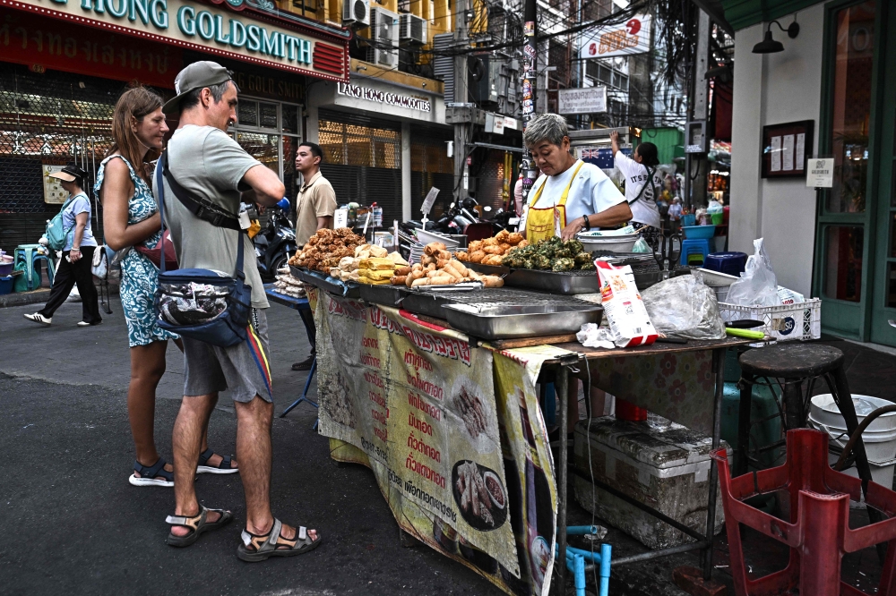 THAILAND-BANGKOK-FOOD-CULTURE-ECONOMY
Content :This photo taken on April 29, 2026 shows street food vendor Thitisakulthip Sang-uamsap selling fried vegetarian snacks to visitors in Chinatown in Bangkok. 
(Photo by Lillian SUWANRUMPHA / AFP) 
 