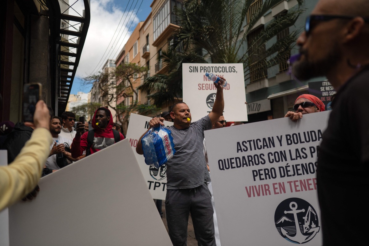 Dockers hold banners reading 'Without protocol, no safety' as they protest against the arrival of a cruise ship affected by hantavirus in Santa Cruz de Tenerife on May 8, 2026. Photo by JORGE GUERRERO / AFP