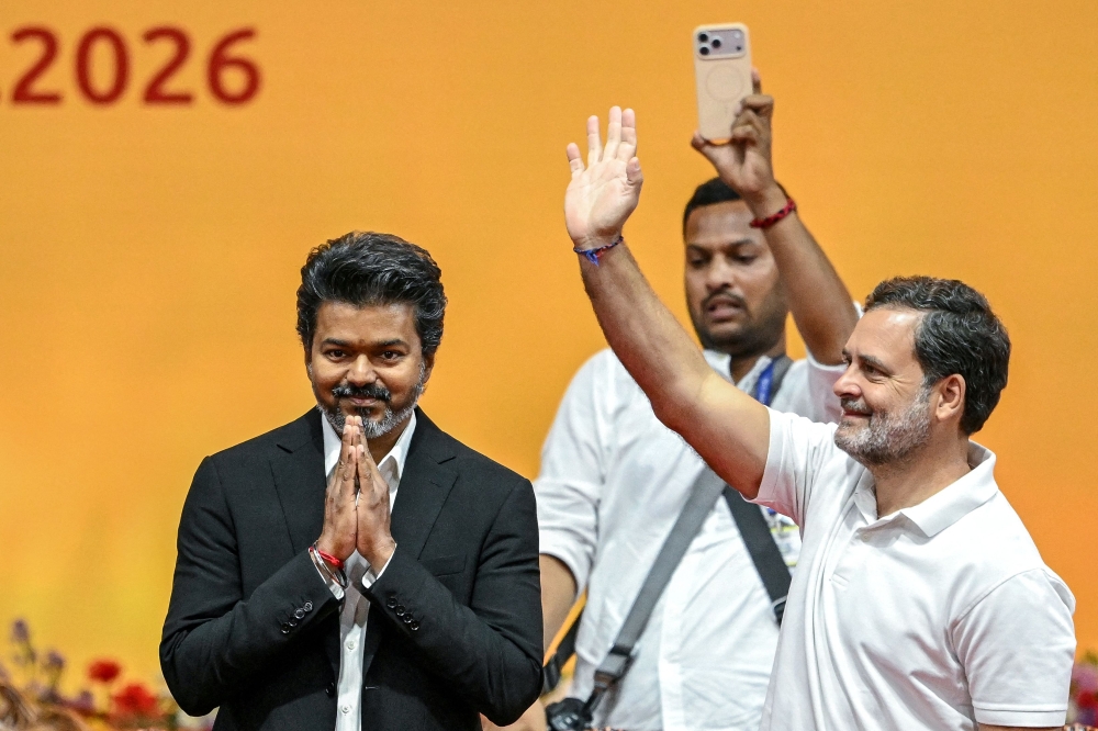 Newly elected chief minister of India's Tamil Nadu state, C. Joseph Vijay (L) along with Indian National Congress (INC) party leader Rahul Gandhi (R) greets supporters after taking the oath during his swearing-in ceremony in Chennai on May 10, 2026. (Photo by R.Satish BABU / AFP)