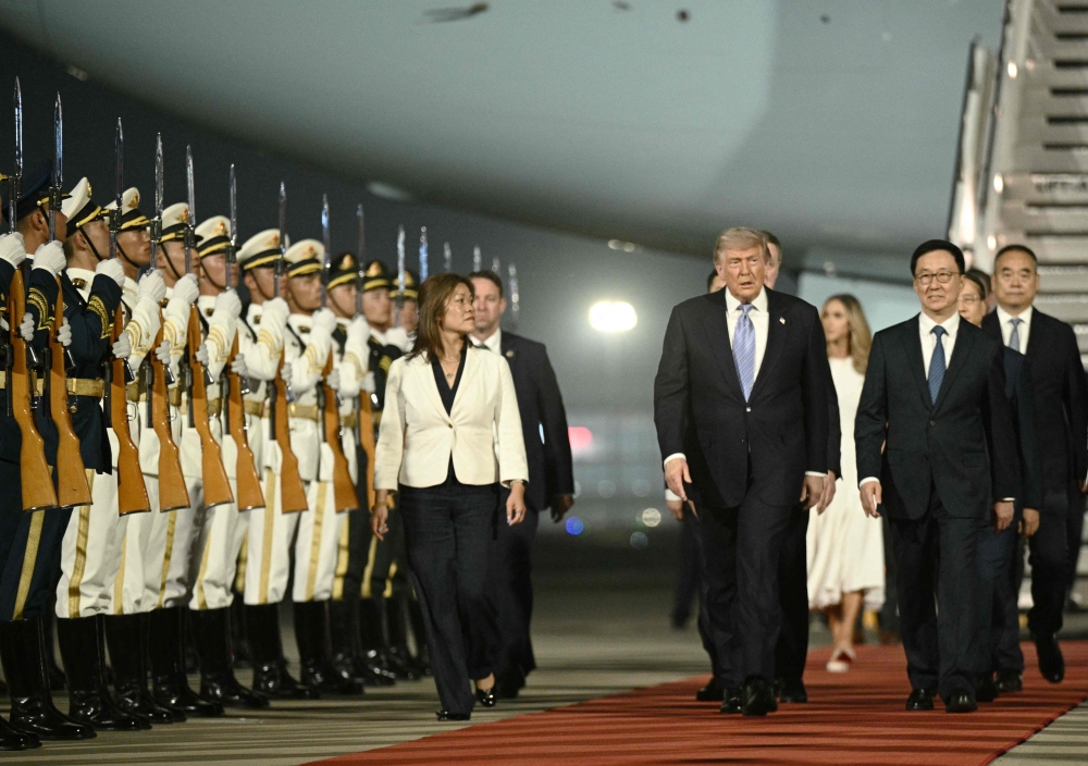 US President Donald Trump (C) is escorted by China's Vice President Han Zheng (R) upon his arrival at Beijing Capital Airport in Beijing on May 13, 2026. (Photo by Brendan Smialowski / AFP)