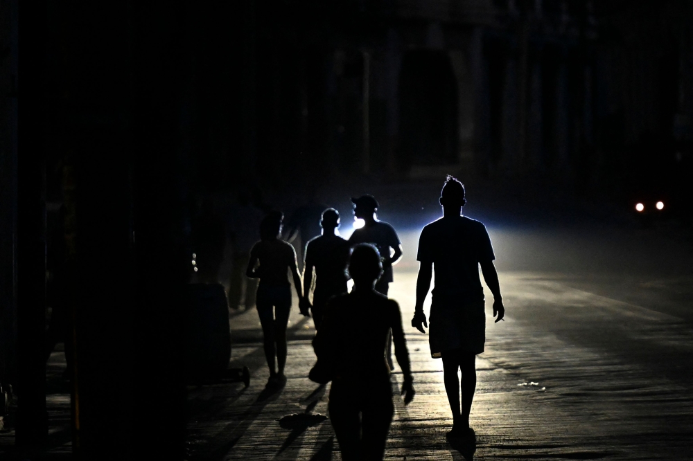 People walk on a street during a blackout in Havana, Cuba. (Photo by Yamil Lage / AFP)